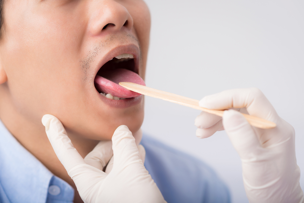 Doctor using tongue depressor on male patient